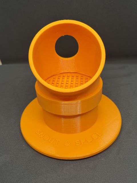 An assembled orange SniffChute: angled entry tube with a nose hole, sitting on a grated base